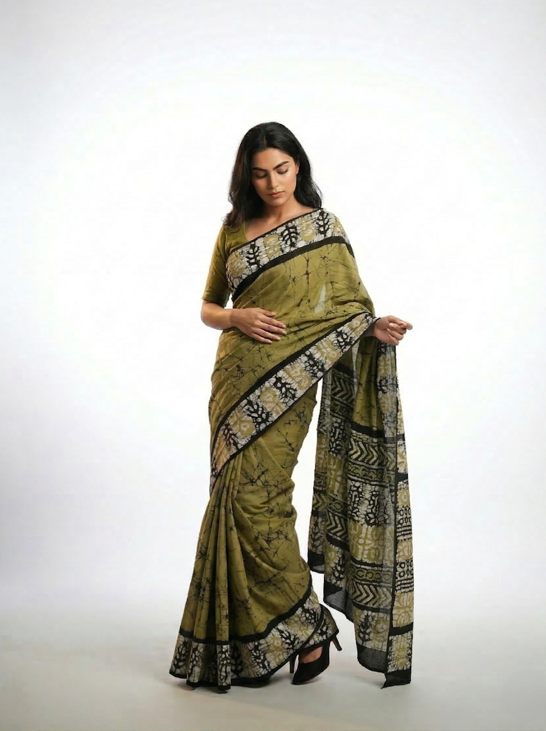 Woman wearing a green saree with black patterns on a white background