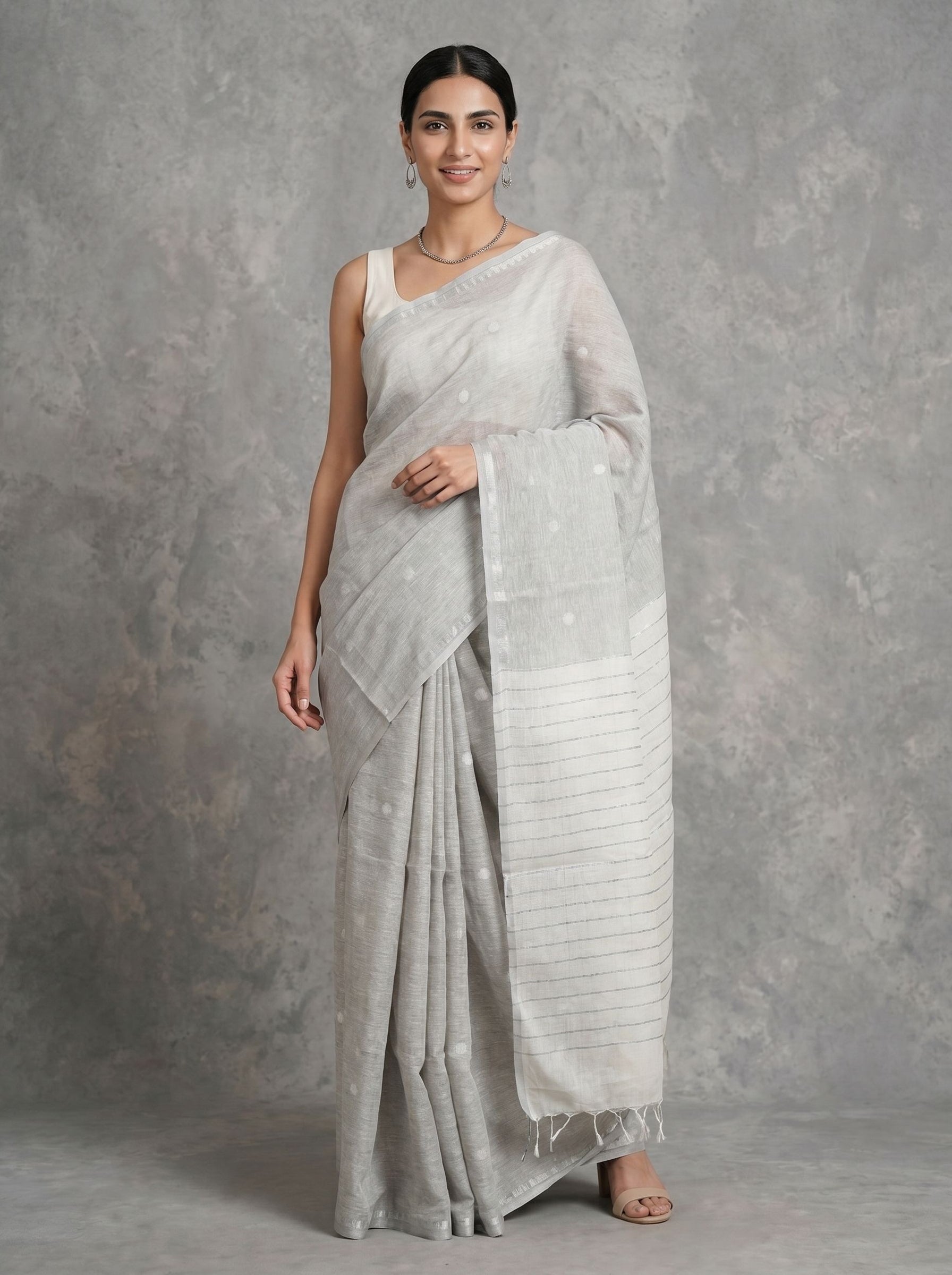 Woman wearing a light gray saree against a gray background