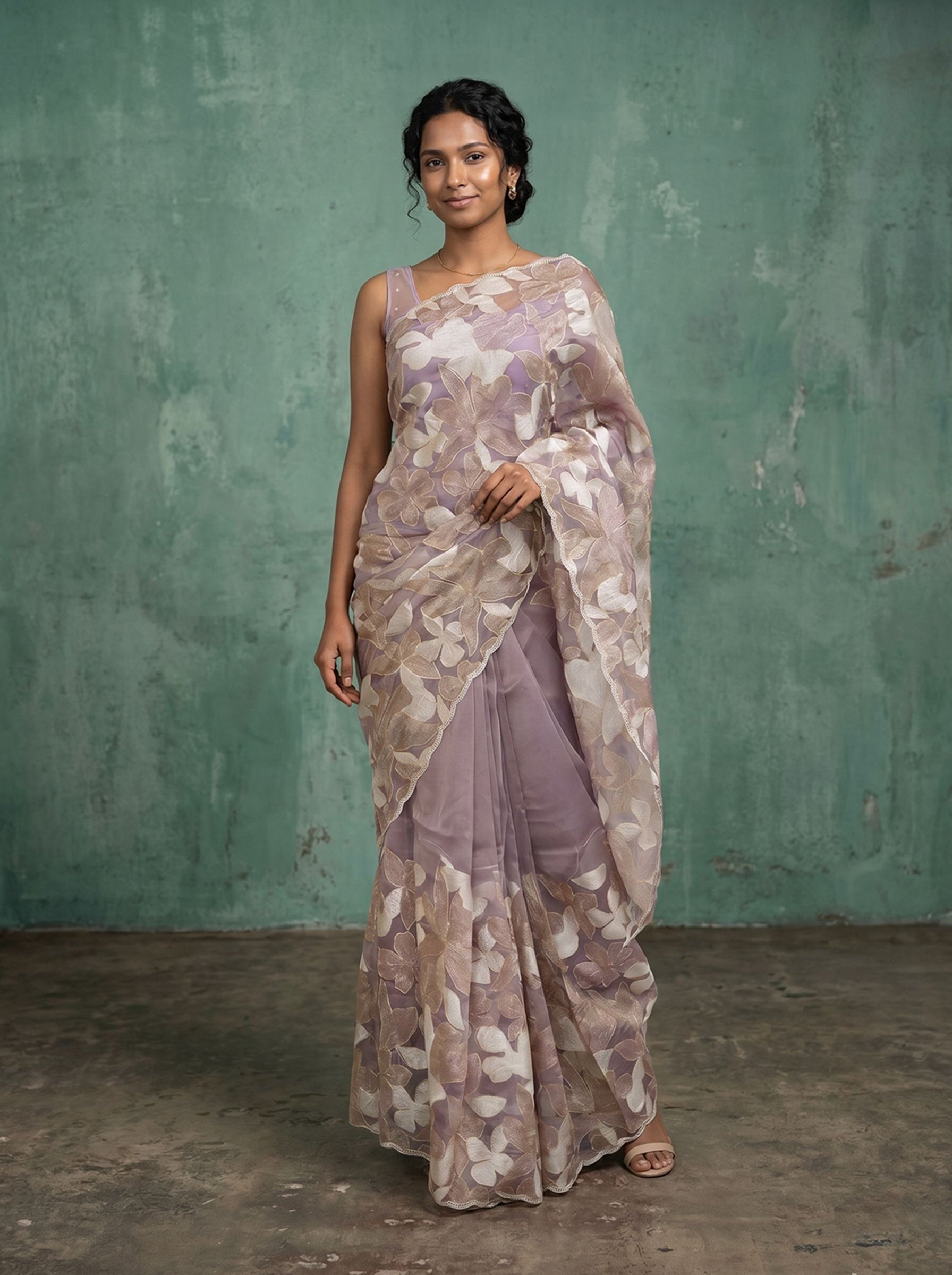 Woman wearing a floral saree against a textured green wall.