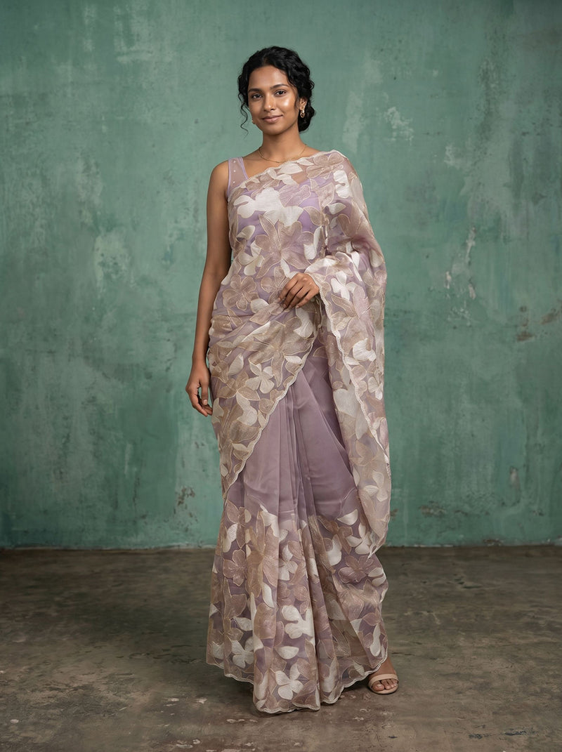 Woman wearing a floral saree against a textured green wall.