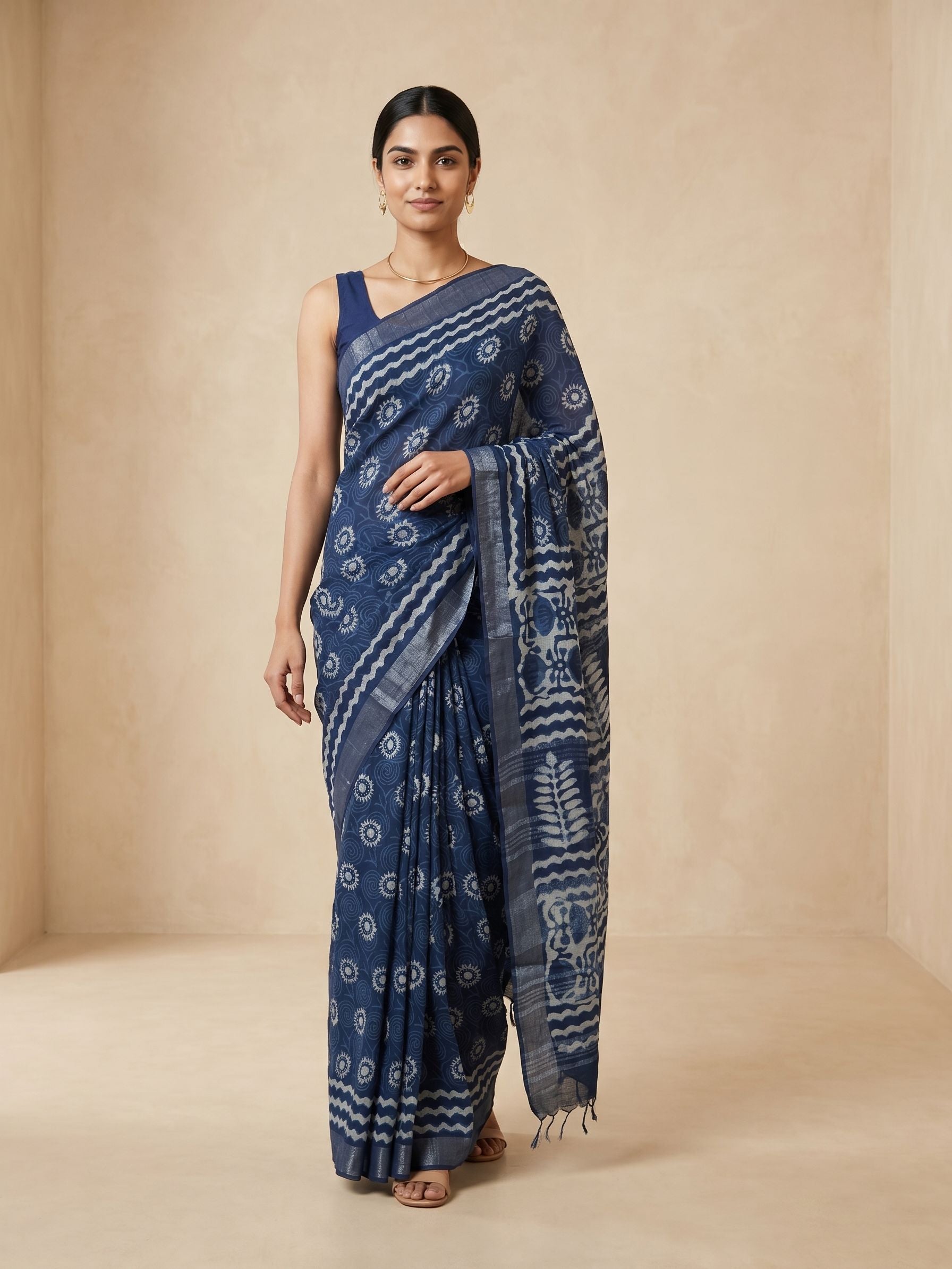 Woman wearing a blue saree with white patterns on a beige background