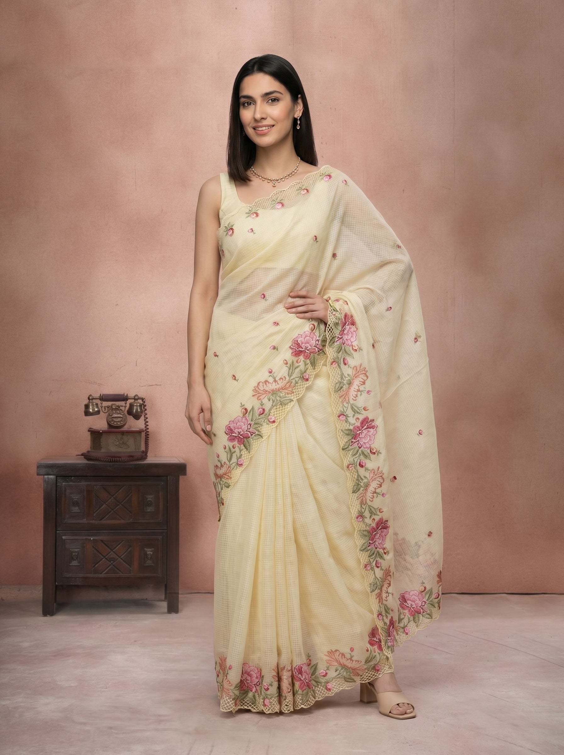 Woman wearing a light-colored saree with floral patterns against a pink background