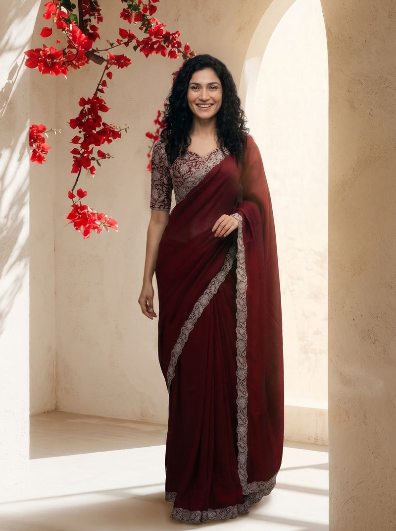 Woman wearing a maroon saree with a floral background