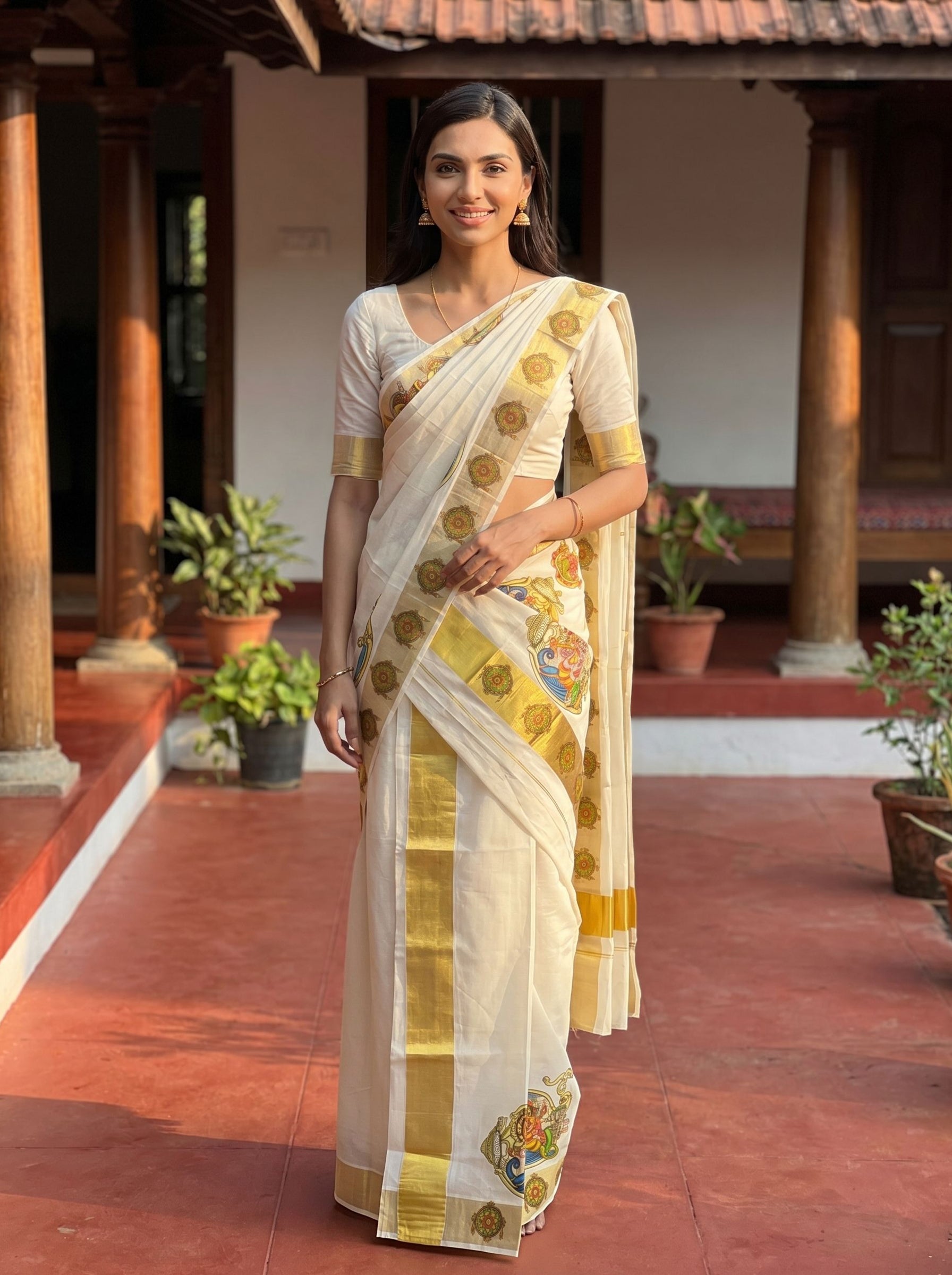 Woman in a traditional saree standing in a sunlit room with plants.