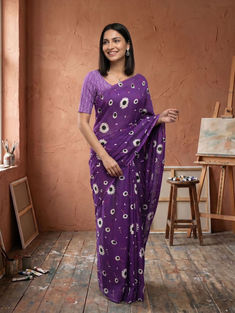 Woman wearing a purple saree with white floral patterns in an artist's studio.