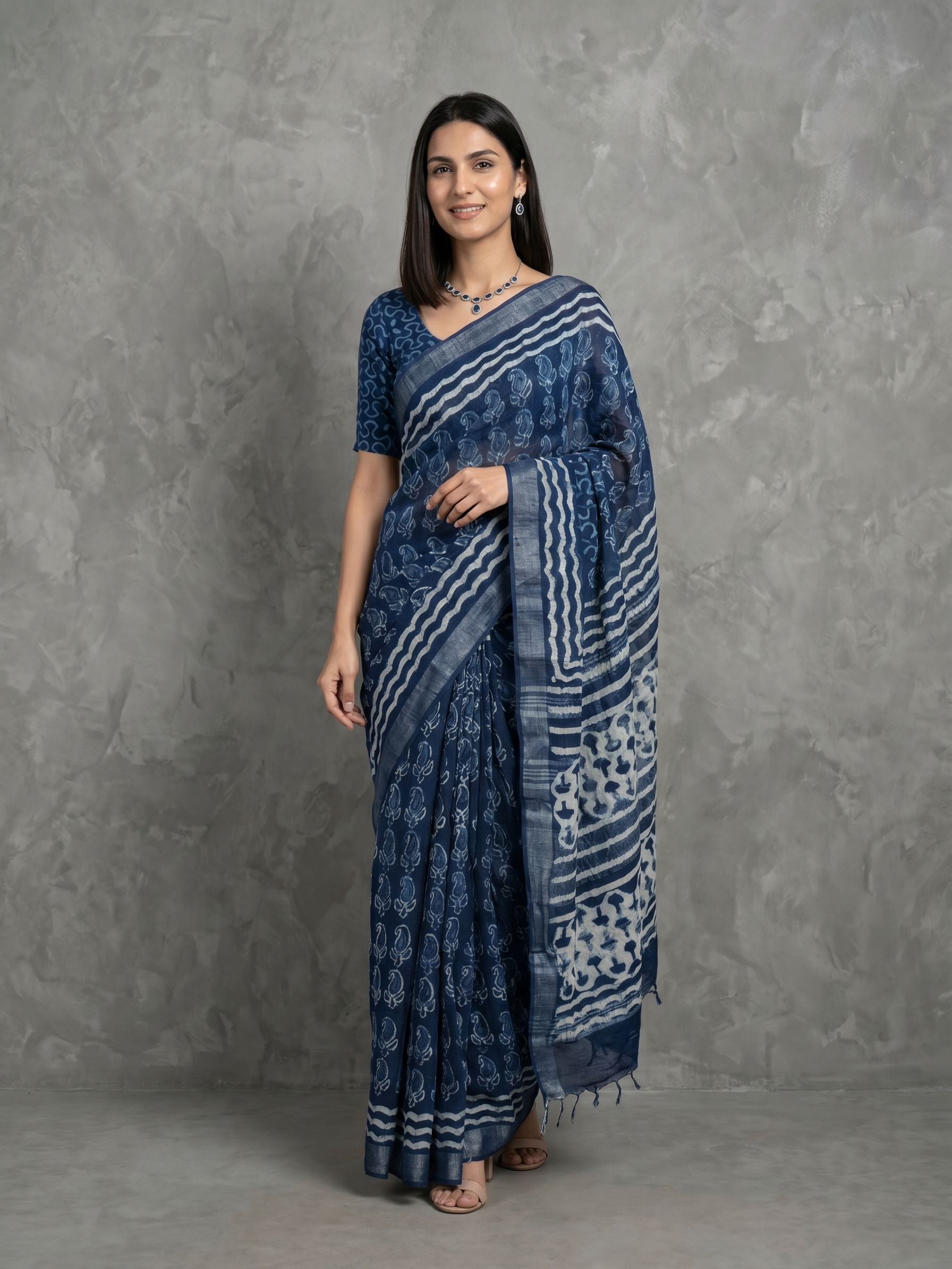 Woman wearing a blue patterned saree against a gray background