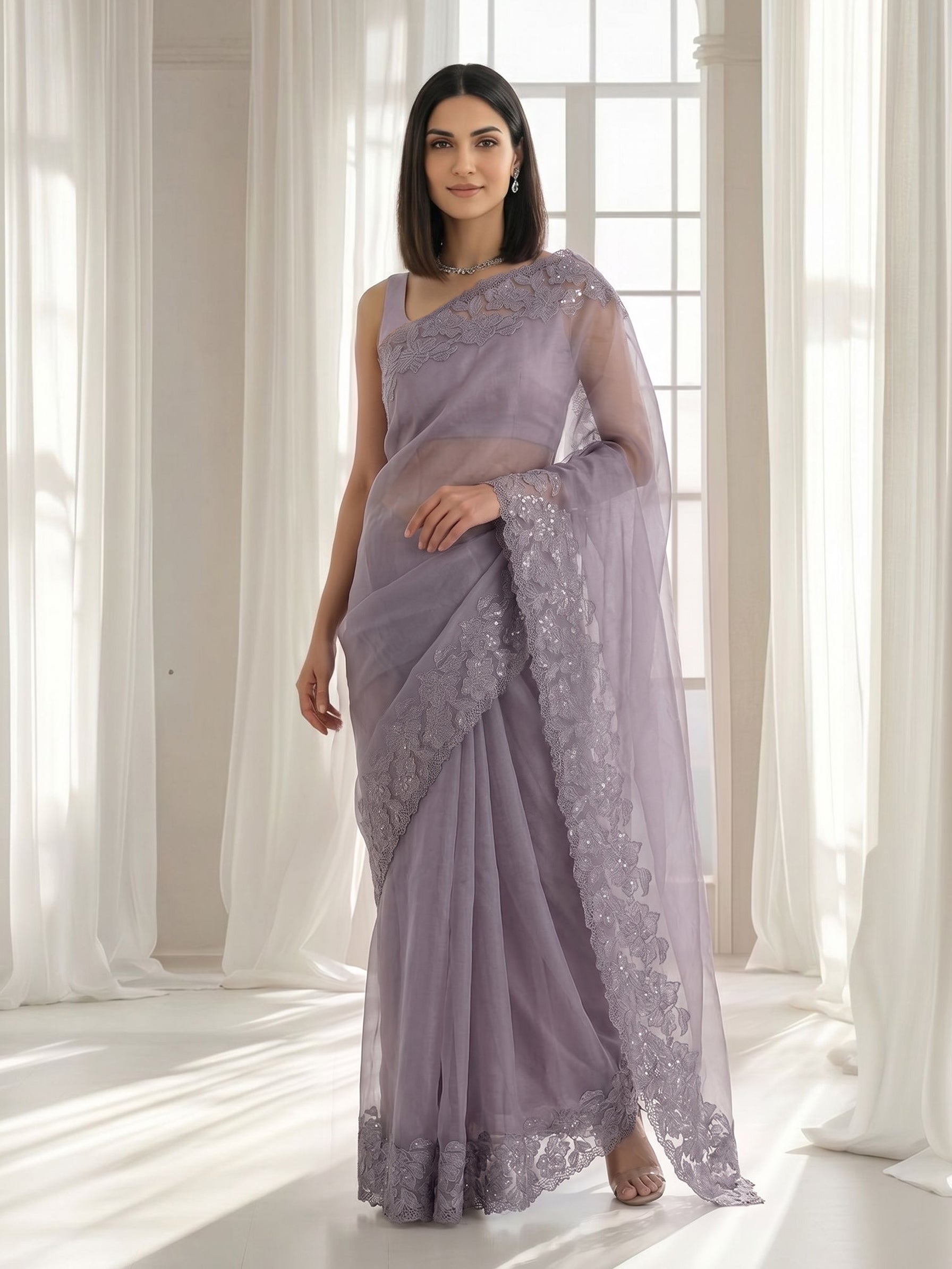 Woman wearing a lavender saree with lace details in a bright room.