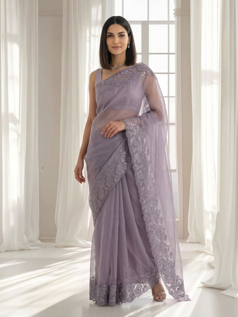 Woman wearing a lavender saree with lace details in a bright room.