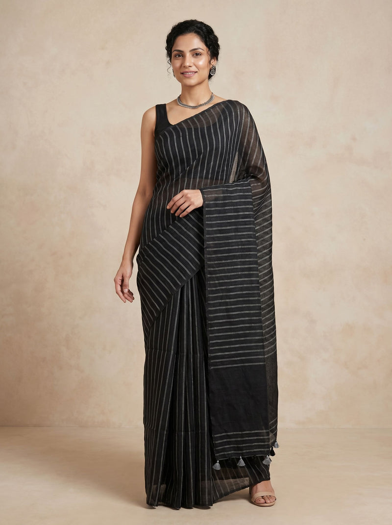 Woman wearing a black saree with white stripes against a beige background