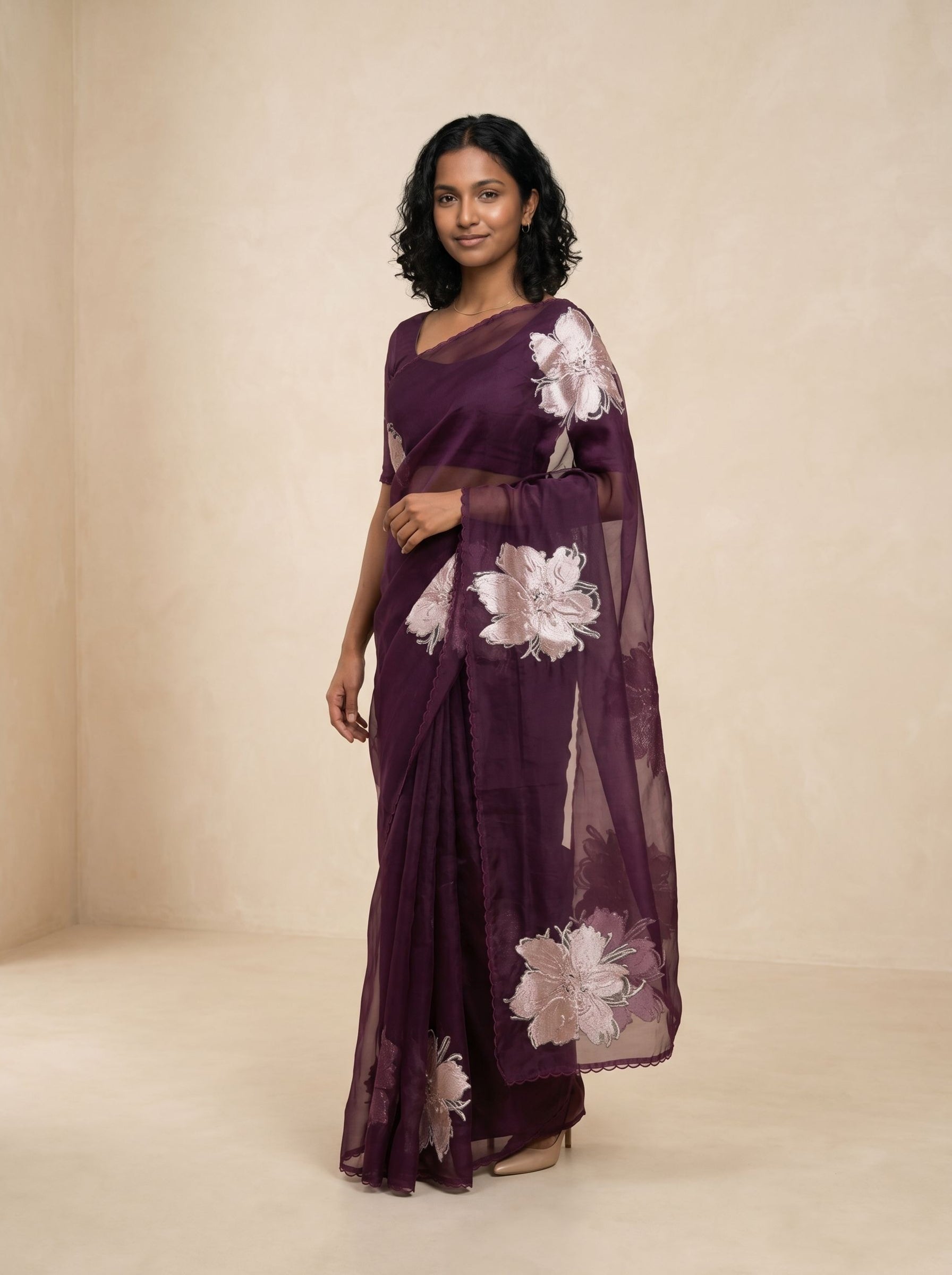 Woman wearing a purple saree with floral patterns on a beige background