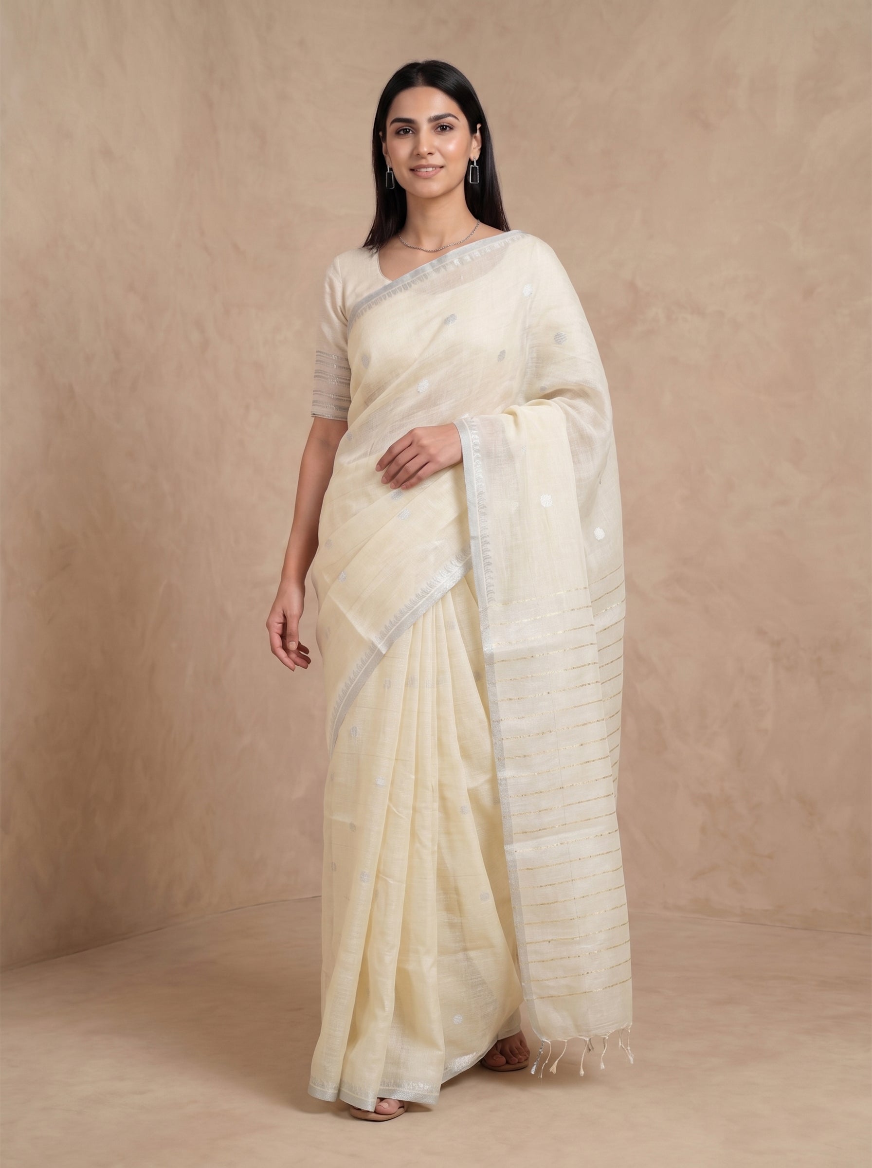 Woman wearing a cream saree with a plain background