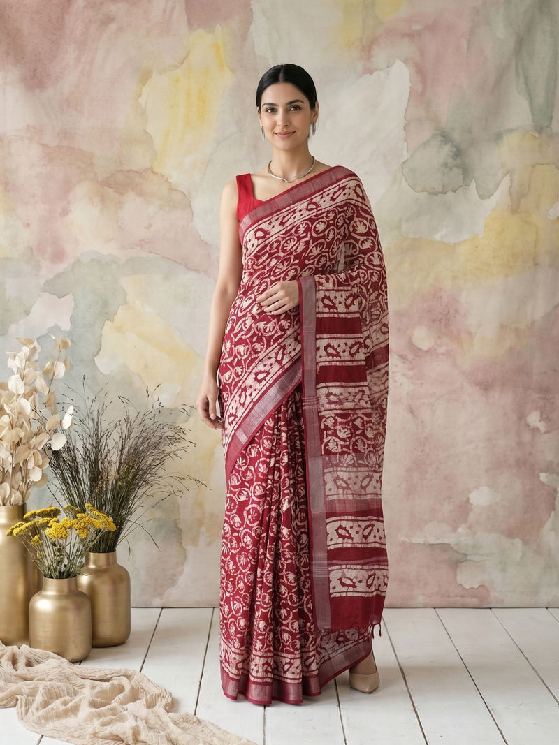 Woman wearing a red and white saree standing against a pastel-colored wall with decorative elements.