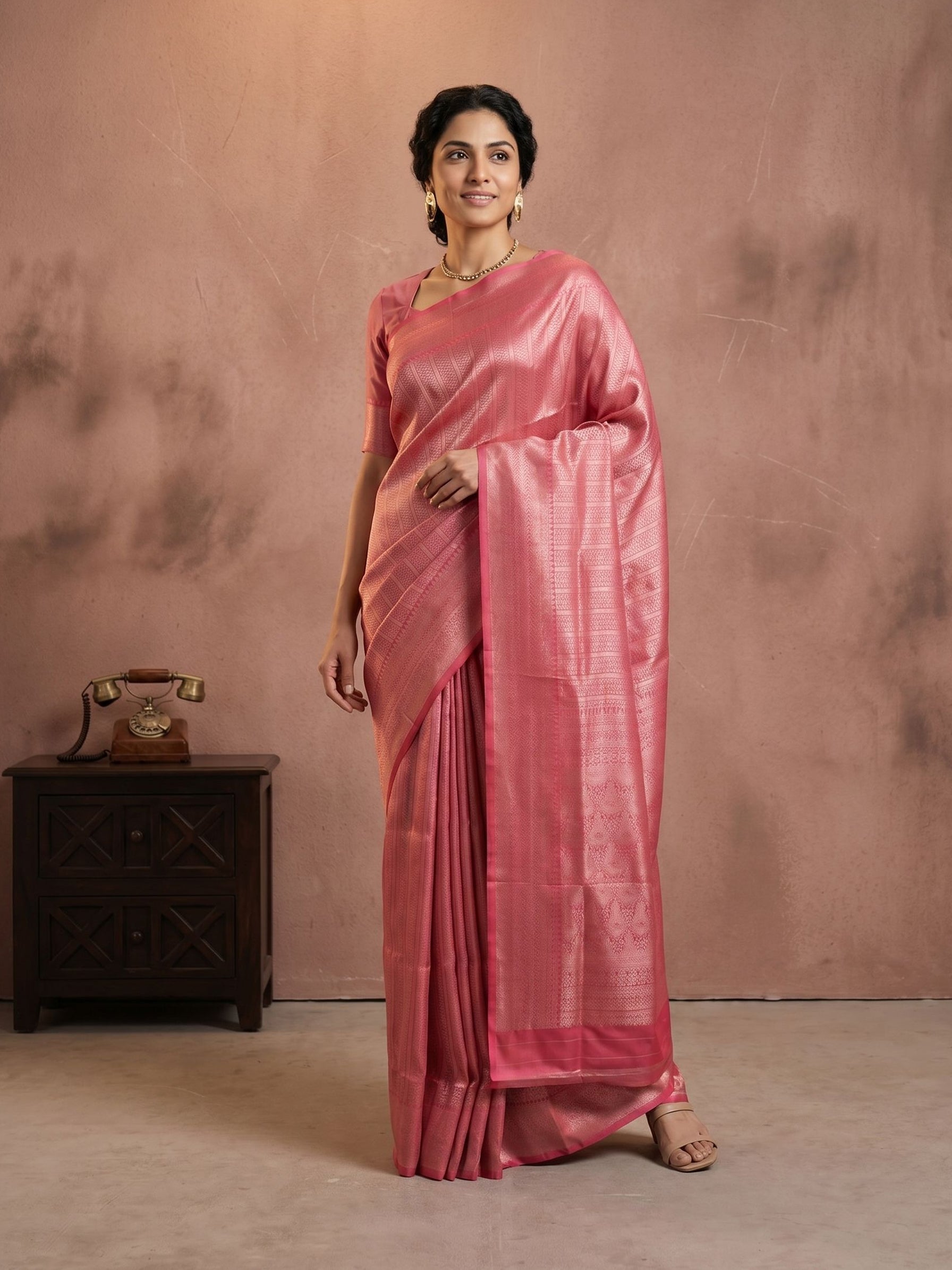 Woman wearing a pink saree against a brown background