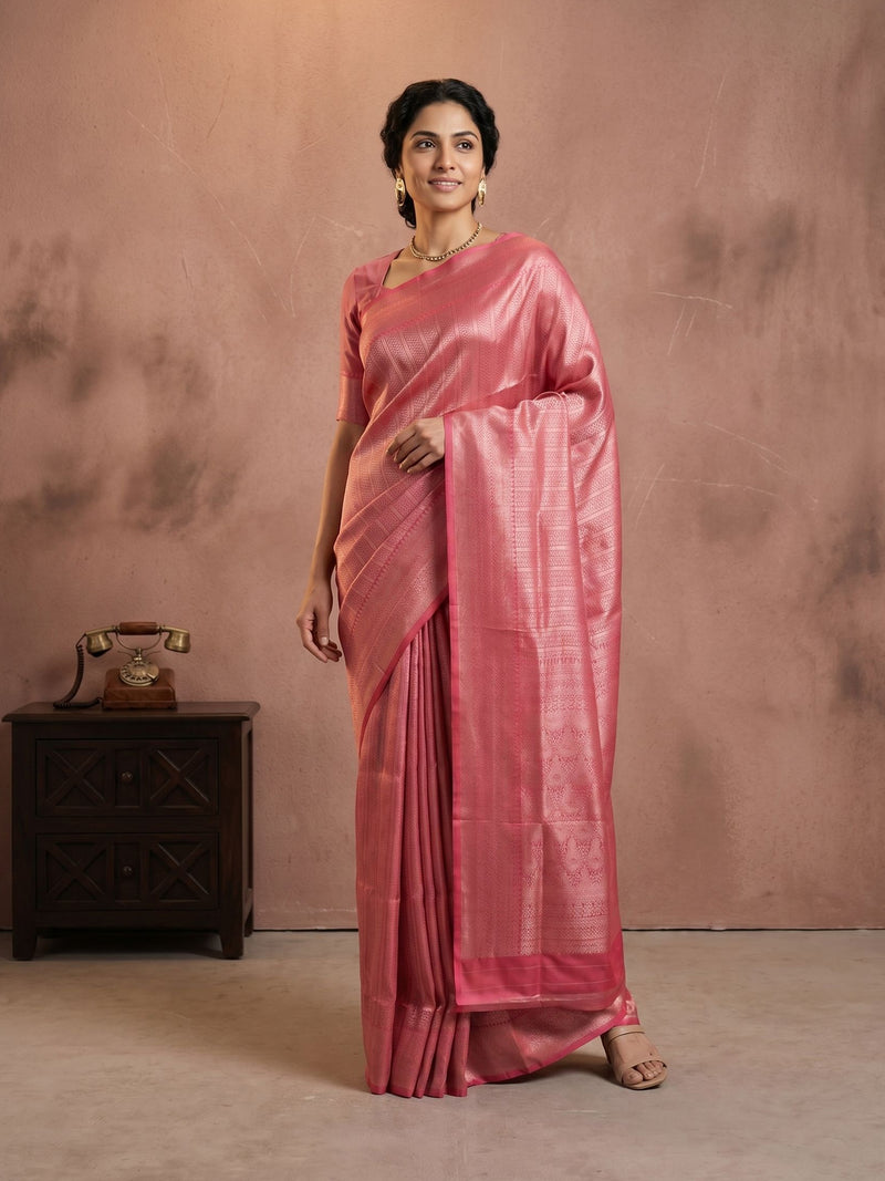 Woman wearing a pink saree against a brown background