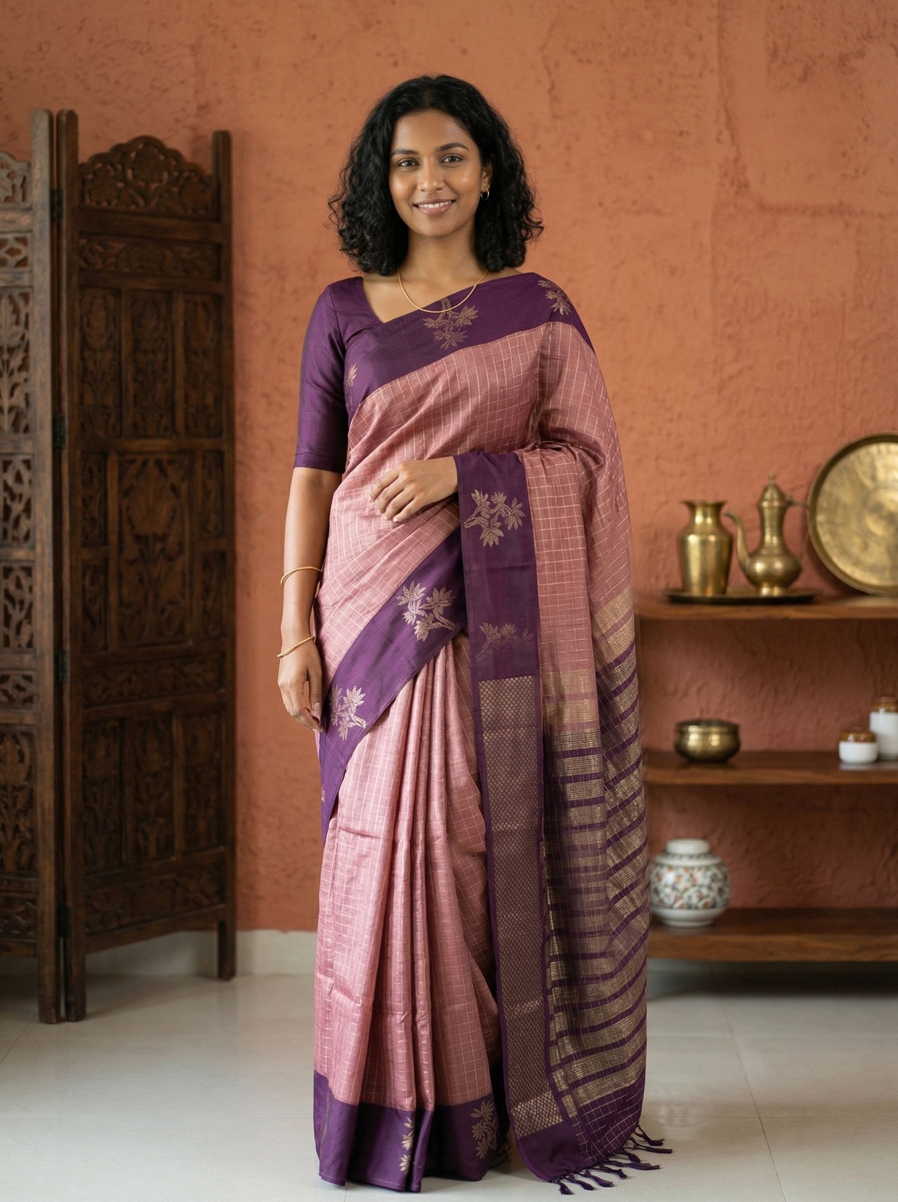Woman wearing a pink and purple saree in a traditional setting