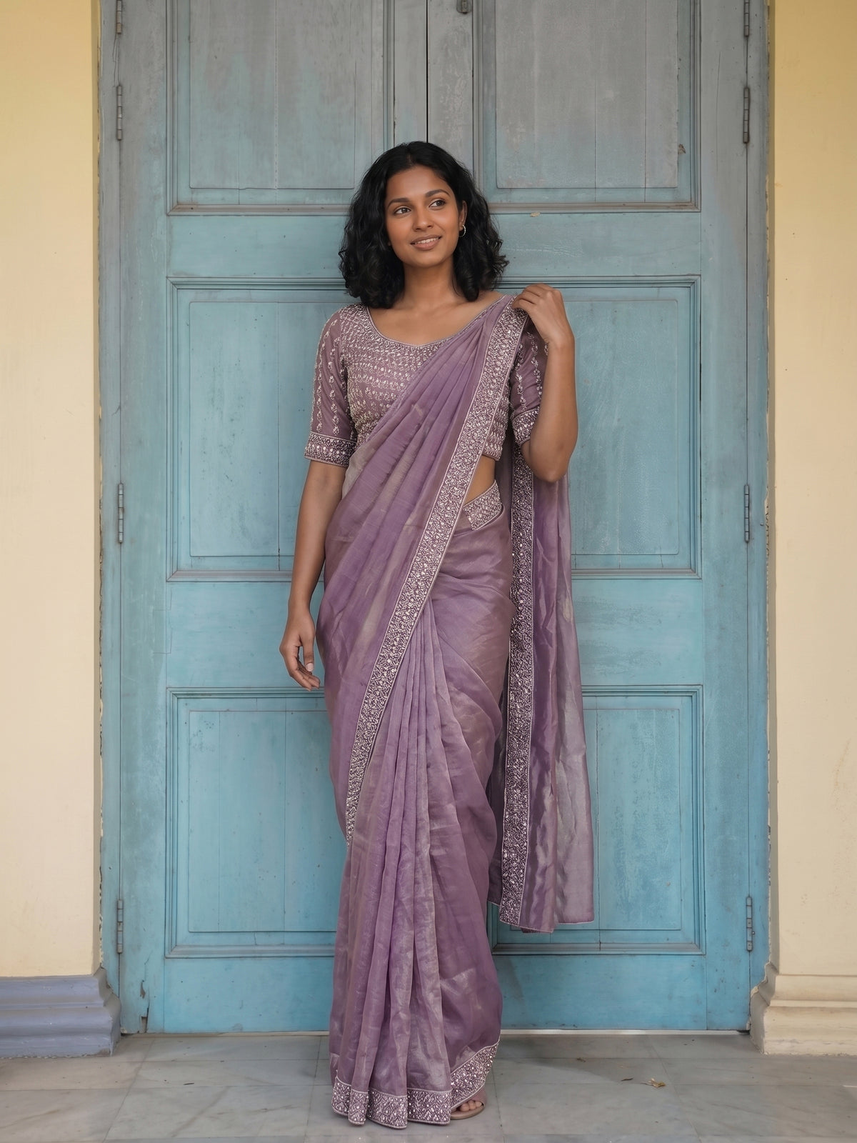 Woman wearing a purple saree with a blue door in the background