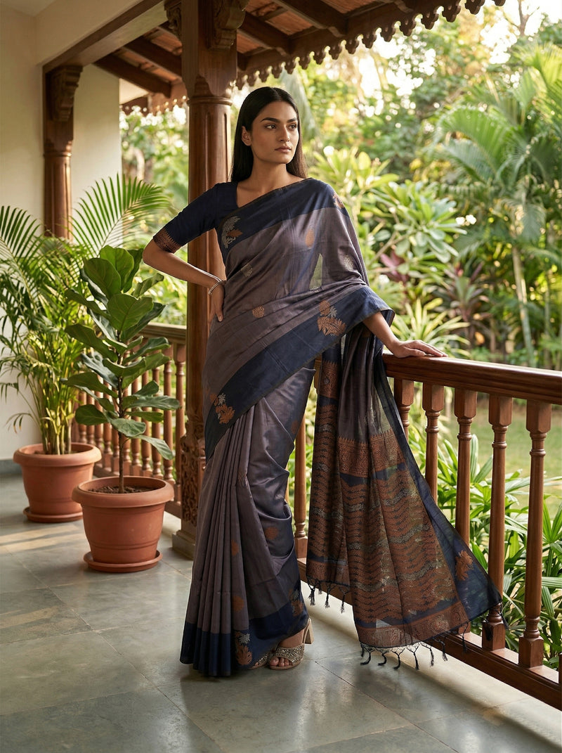 Woman in a traditional saree standing on a balcony with greenery in the background