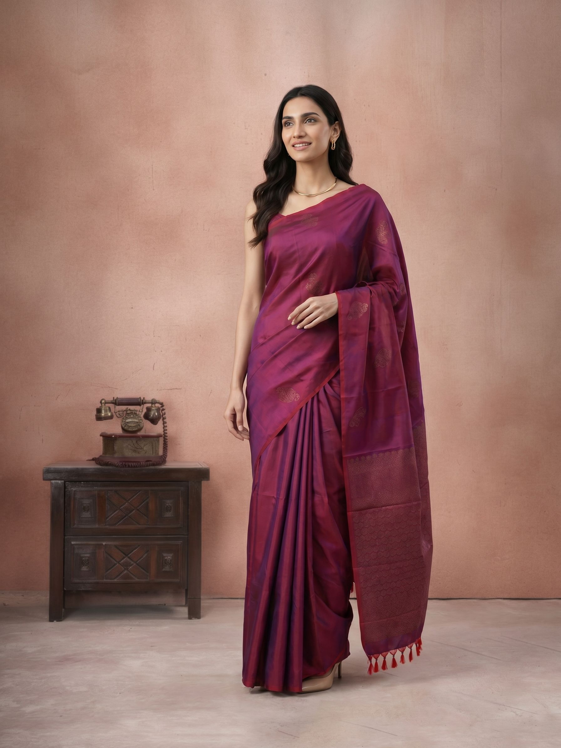 Woman wearing a purple saree standing against a plain background