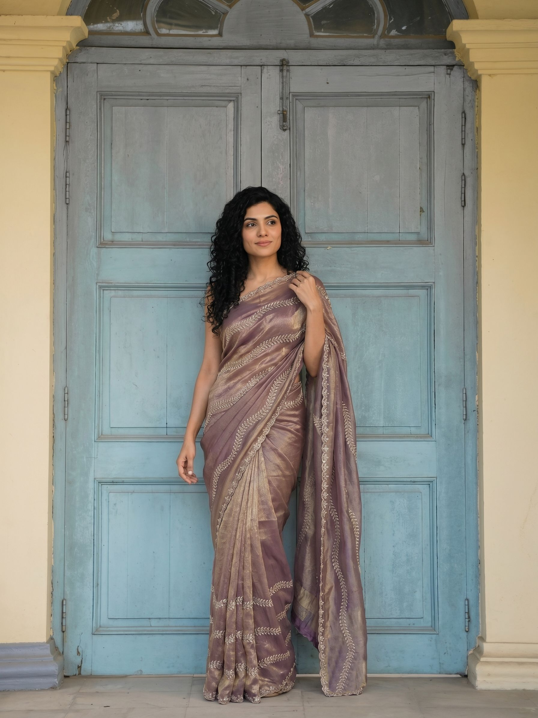 Woman in a saree standing in front of a blue door