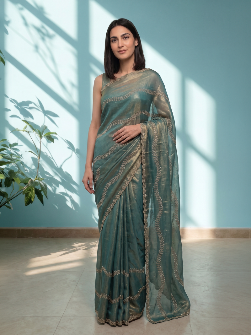 Woman wearing a green saree with a subtle pattern in a well-lit room.