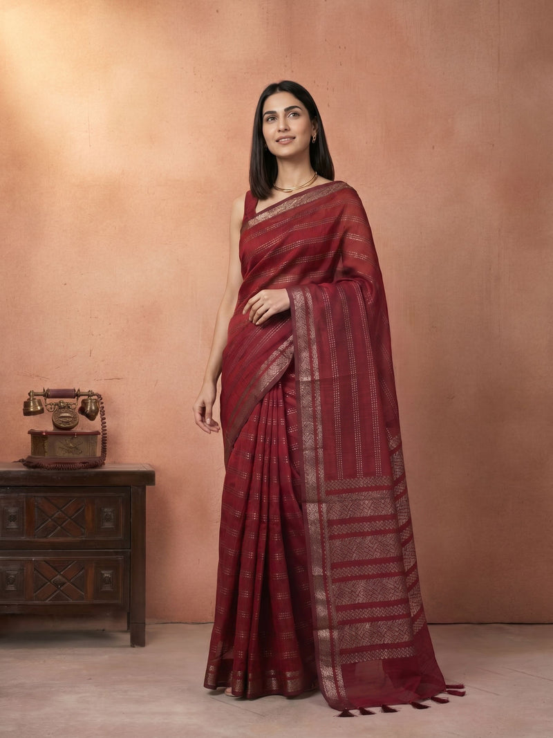 Woman wearing a maroon saree with a wooden chest in the background