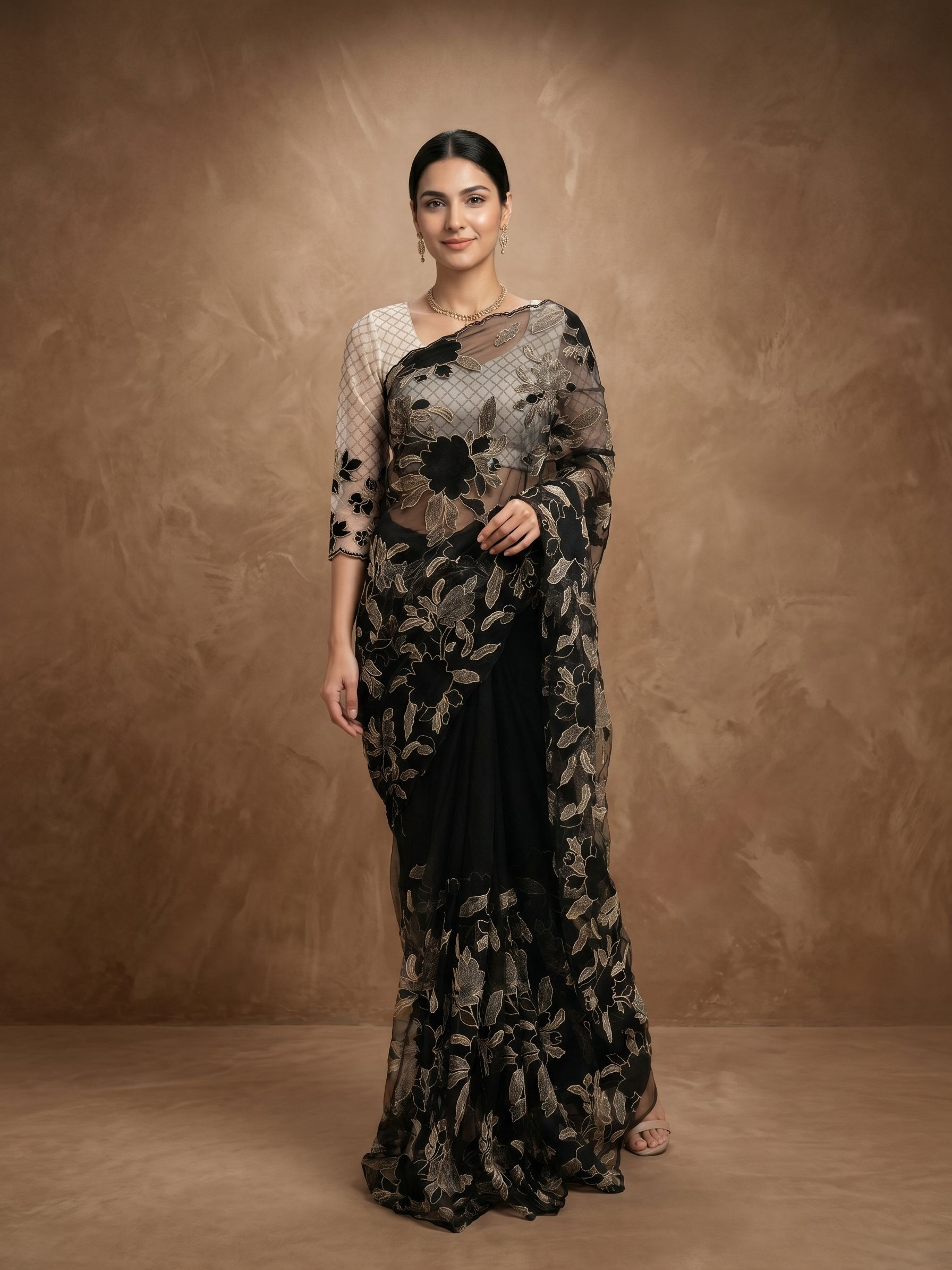 Woman wearing a black floral saree against a brown background