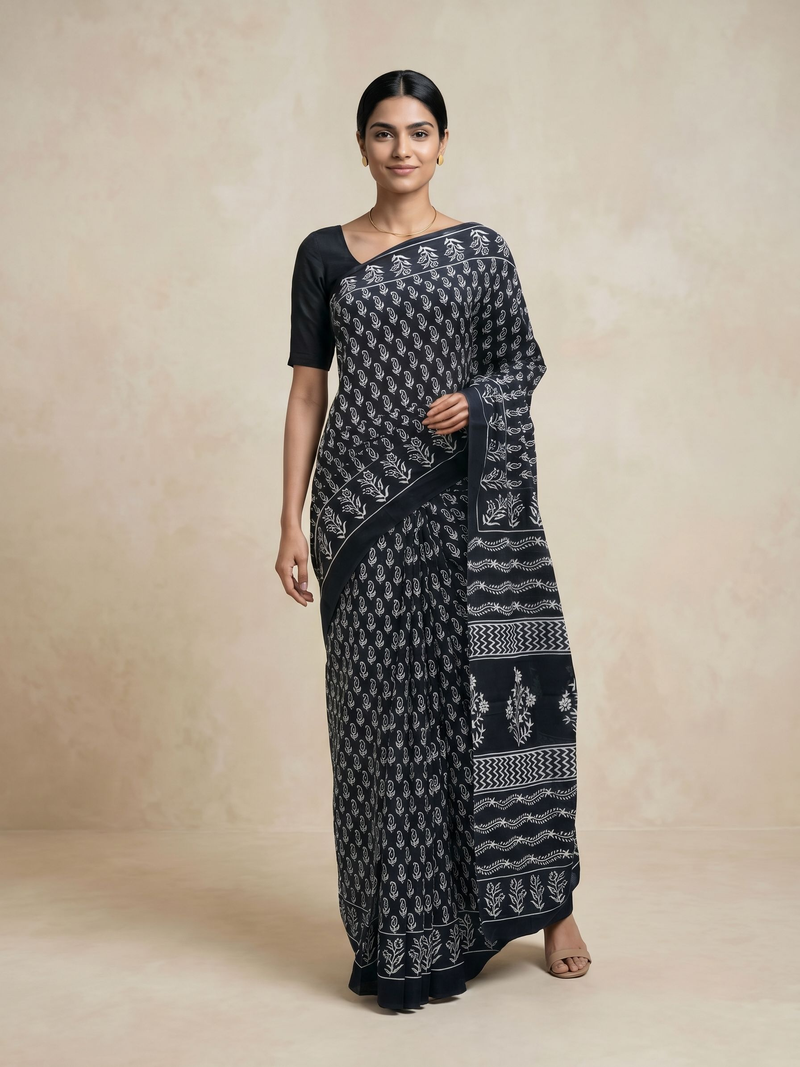 Woman wearing a black and white patterned saree on a beige background