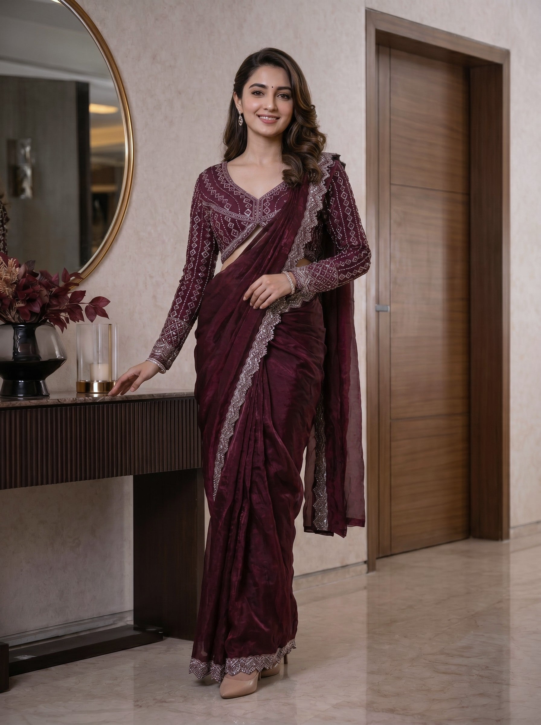 Woman in a maroon saree with silver border standing indoors.