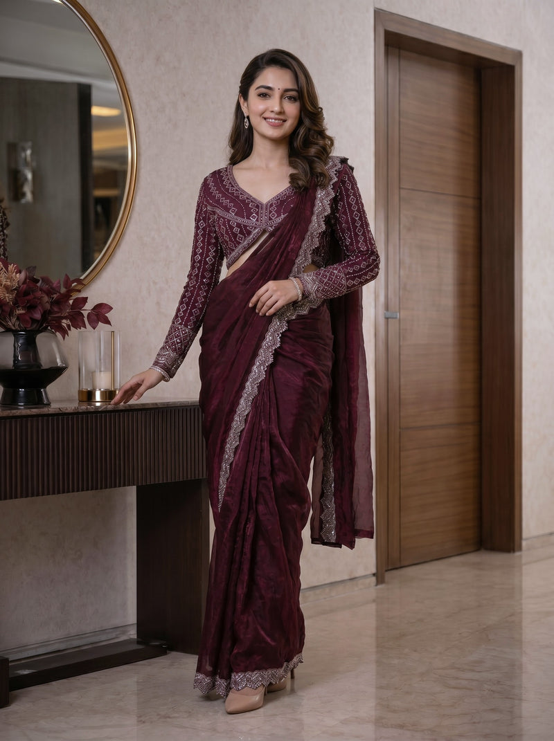Woman in a maroon saree with silver border standing indoors.