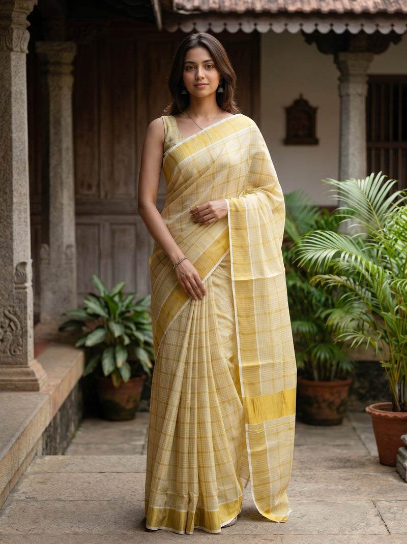 Woman in a yellow saree standing in an outdoor setting with plants.