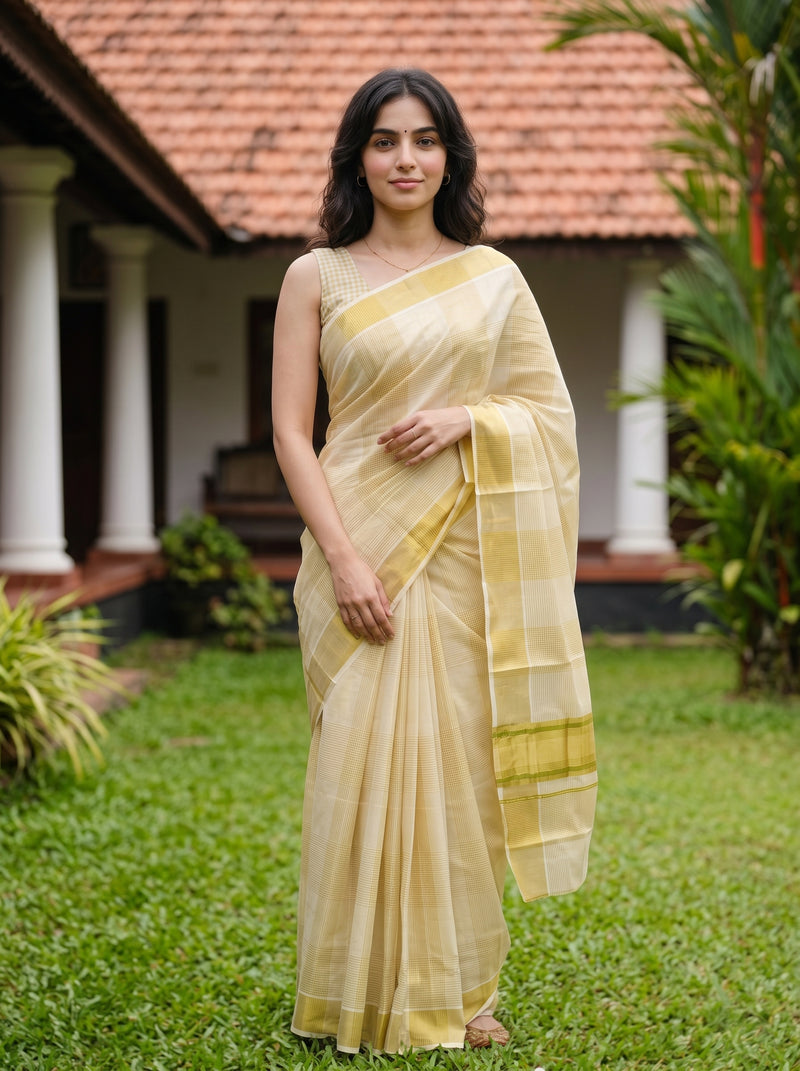 Woman in a traditional saree standing outdoors with a house and plants in the background