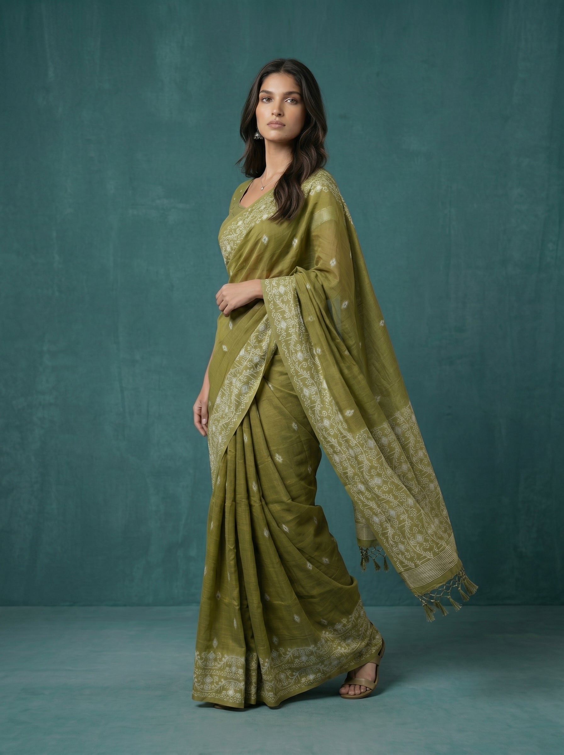 Woman wearing a green saree with a matching blouse against a teal background