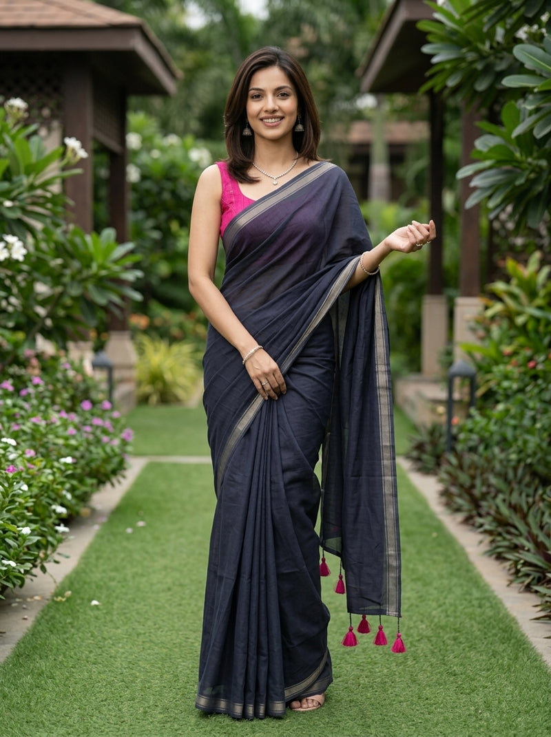 Woman in a dark blue saree with pink blouse standing in a garden setting