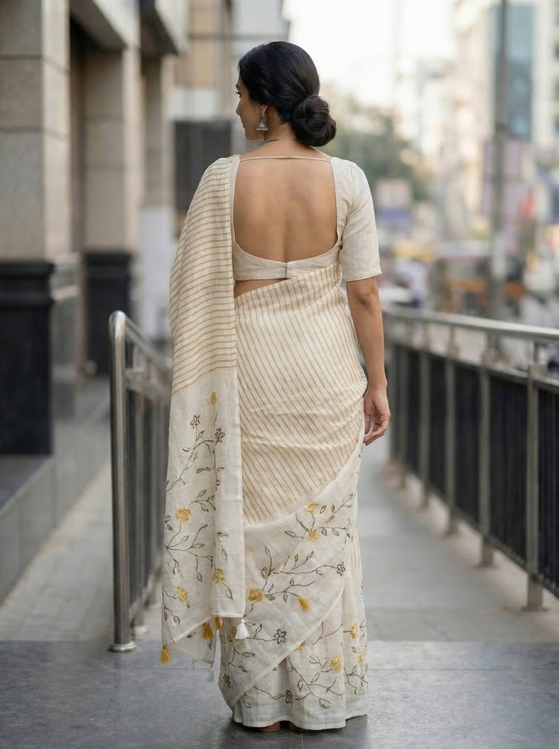 Woman in a white saree with floral patterns walking on a city street.
