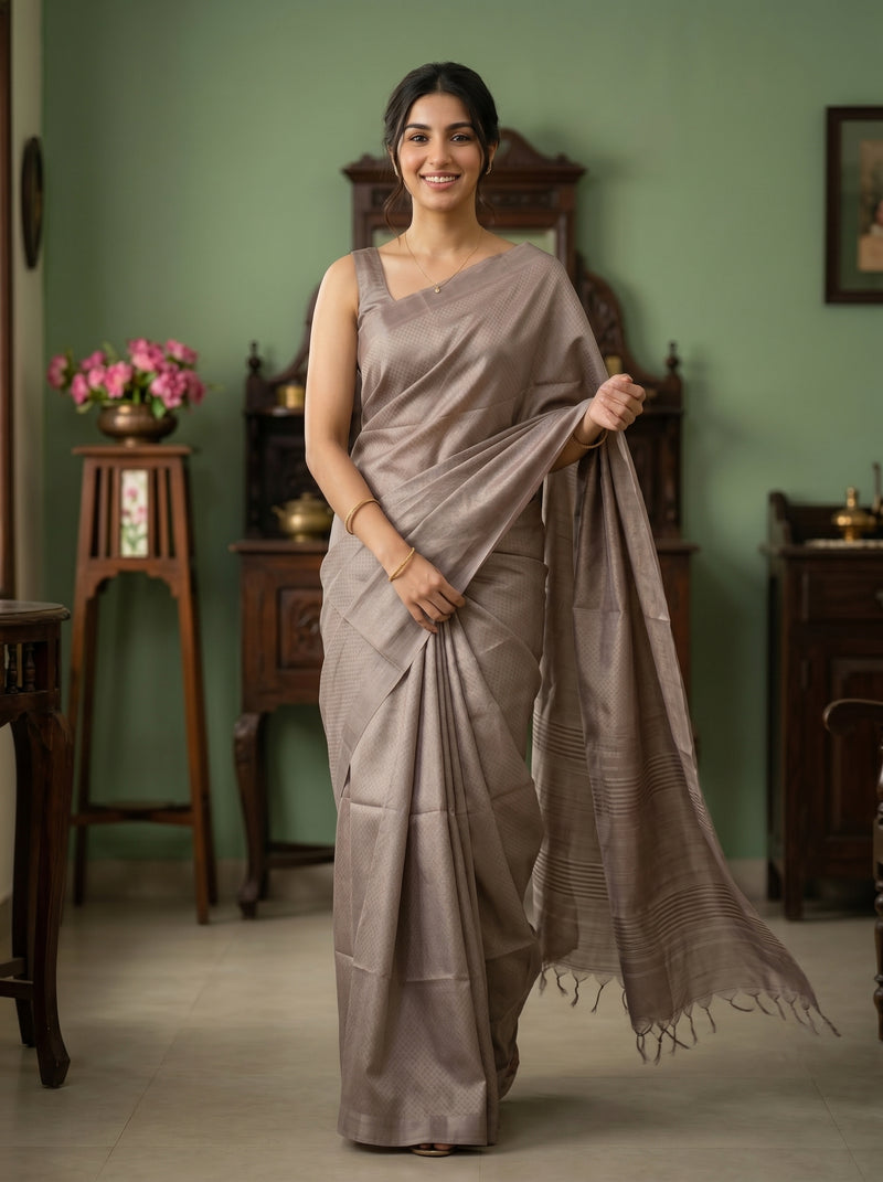 Woman in a gray saree standing in a room with green walls and wooden furniture.