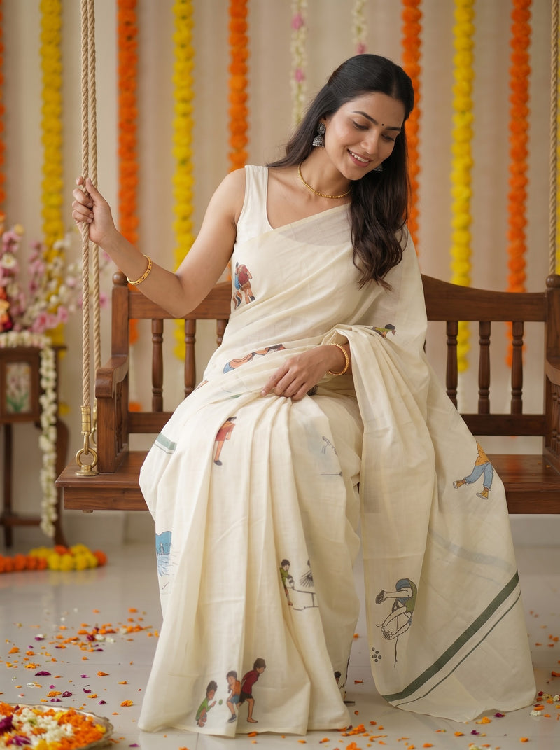 A woman wearing a cream-colored printed saree sits on a wooden swing decorated with orange and yellow marigold garlands. The saree features delicate hand-painted motifs of children and birds, with a green border stripe.