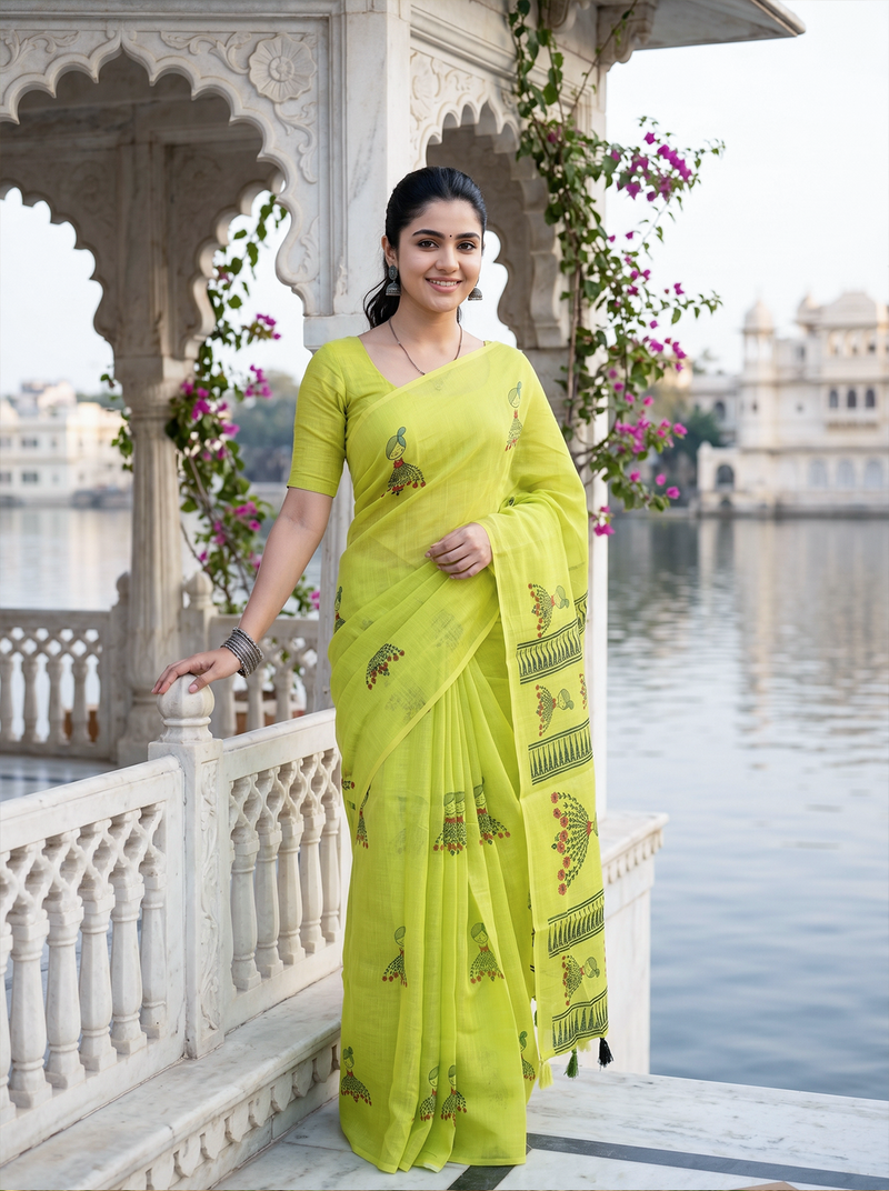 Woman in a bright green saree with floral patterns standing in front of an architectural structure with floral decorations.