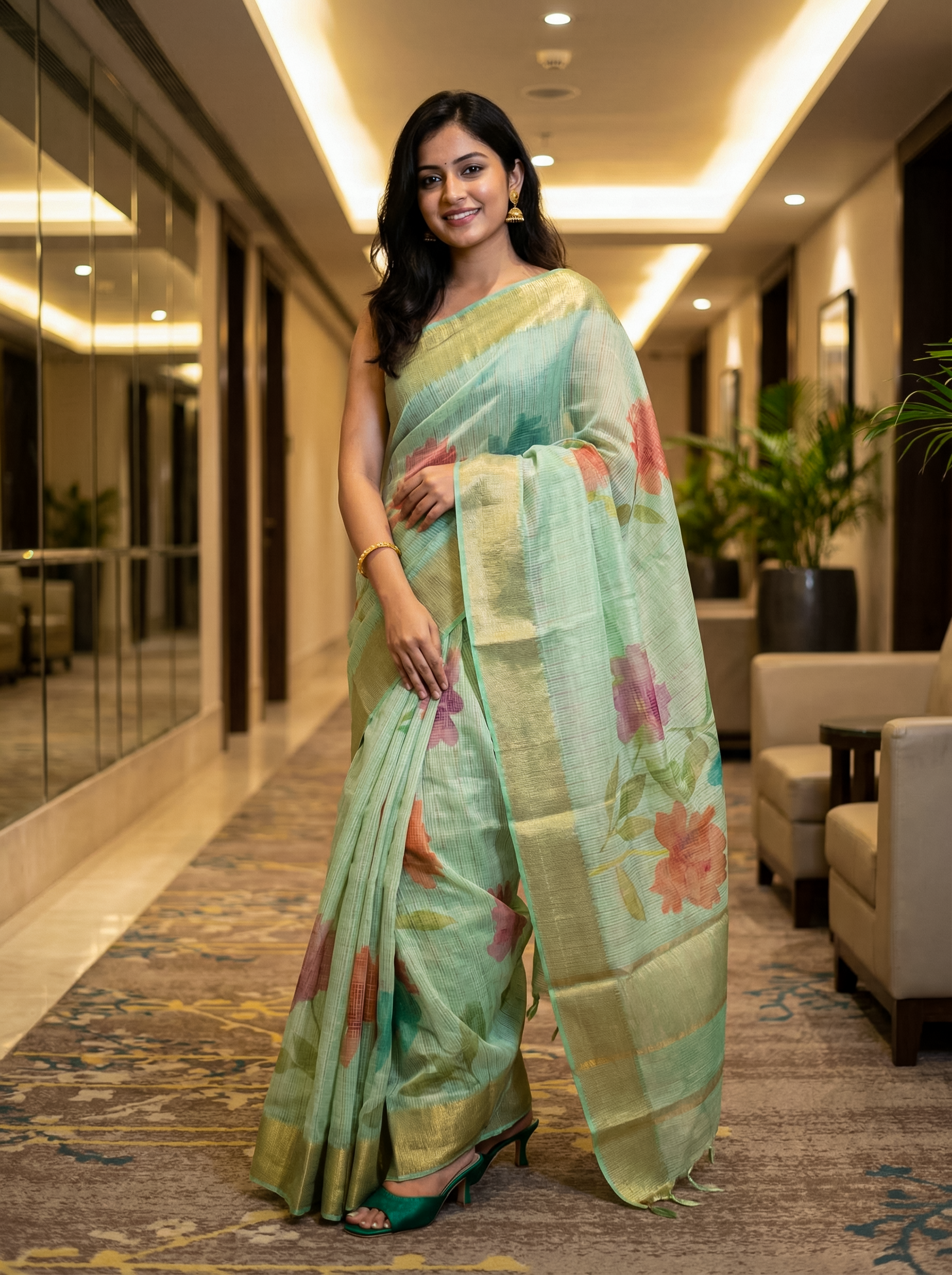 Woman in a light green saree with floral patterns in an indoor setting
